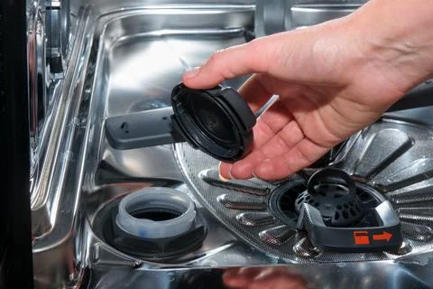Woman hand adding salt to dishwasher water softener container. Kitchen applia Photos