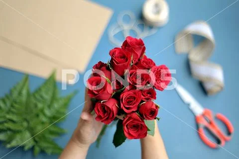 A woman hand arrange the fresh red roses for bouquet Stock Photos