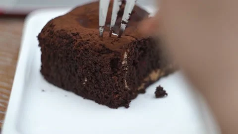 Woman hand breaks off a piece of chocolate cake with a fork Stock Footage 147596341