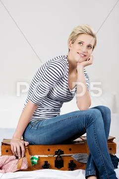 Woman with hand on chin sitting on overloaded baggage Stock Photos