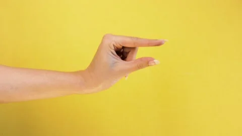 Woman hand gesture showing small size with two fingers, over yellow background. Stock Footage 132081353