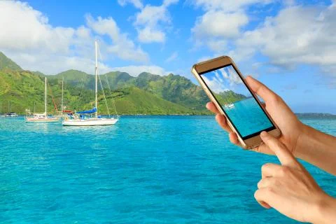 Woman hand hold and touch screen smart phone over Beautiful sea and sailing.. Stock Photos