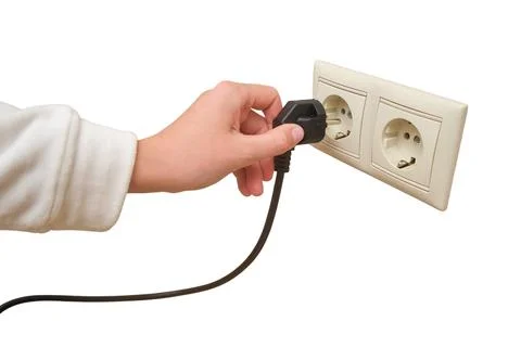Woman hand inserting electrical plug into wall socket. Household appliance co Stock Photos