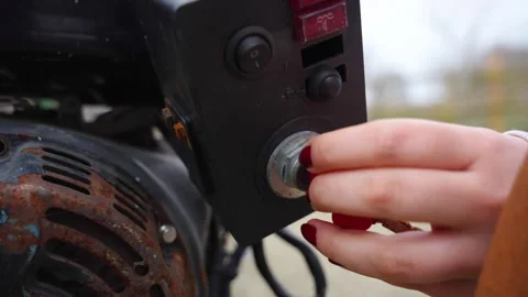 Woman hand inserting a red key into the ignition switch of rusty portable power Stock Footage 319791739