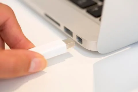 Woman hand inserting thunderbolt cable on computer Fotos de archivo