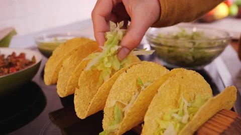 Woman hand making tacos - adding the base layer of lettuce 動画素材 131587249