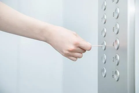 Woman hand presses elevator button with sweep. Concept coronavirus disinfection Photos