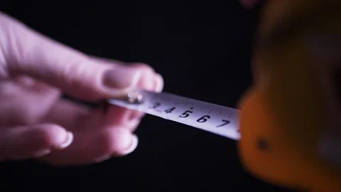 Woman Hand Pulling Out a Retractable Measuring Tape on Black Background Stock Footage 338998382