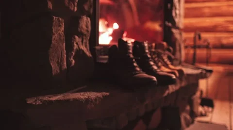 Woman Hand puts Winter Boots on a Shelf near Cozy Burning Fireplace. 4K. Stock Footage