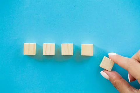 Woman hand putting and stacking blank wooden cubes on desk with copy space for Stock Photos