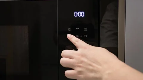 Woman hand setting timer on the microwave display and the countdown close up Stock Footage 268862374