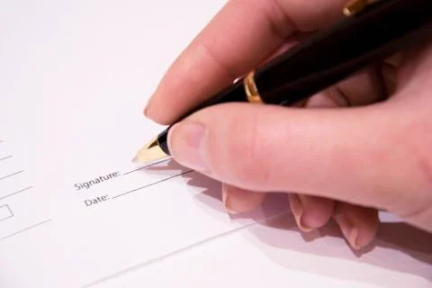 A woman hand signs a paper business pen. Stock Photos