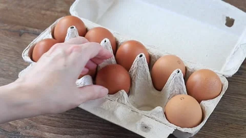 Woman Hand Sorting Fresh Brown Eggs in Cardboard Box on Wooden Background Stock Footage 346243356