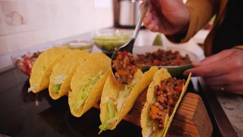 Woman hand stuffing taco shells with ground meat and vegetables filling 動画素材 131587340