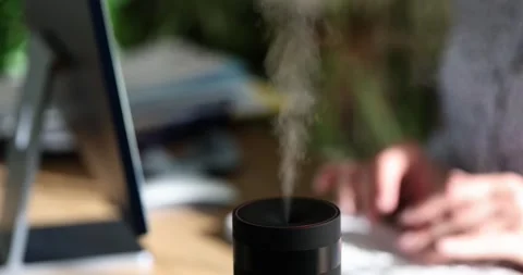 Woman hand is typing on computer keyboard and diffuser diffuses fresh scent Stock Footage 249879644