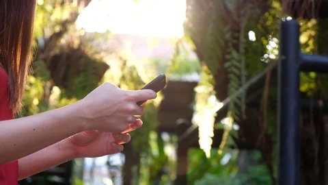 Woman hand using cell phone at the park sunset background, outdoor, slow motion, Stock Footage 107709612
