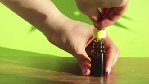 Woman hand using dropper with   cbd  oil dripping in to glass bottle close up Stock Footage 135380107