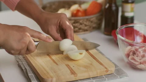 Woman hand using knife to cut white onion on wooden cutting board. Stock Footage 242549566