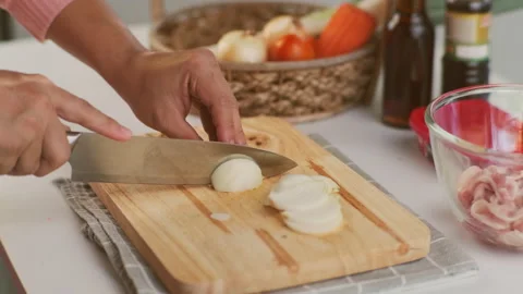 Woman hand using knife to cut white onion on wooden cutting board.  Stock Footage 242549683