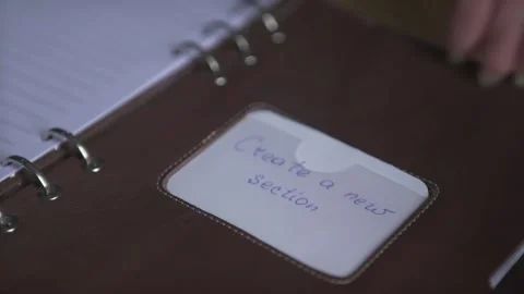 Woman hand using light brown leather note book pad sticker daily planner habit t Stock Footage 137539002