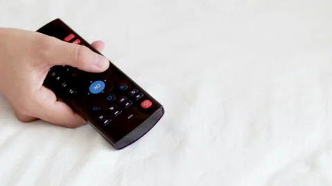 Woman hand using remote control from tv pressing the ok or volume button Stock Footage 202600080