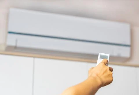 Woman hand using remote control open air conditioning. Stock Photos