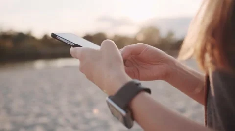 Woman Hand Using Smartphone and wearing Smartwatch. SLOW MOTION. Lens Flare Stock Footage 68544743