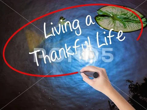 Woman Hand Writing Living a Thankful Life with marker over trans Stock Photos