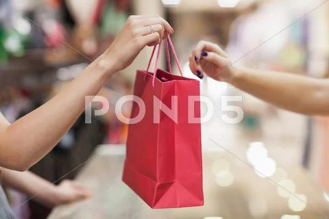 Woman handing over shopping bag Stock Photos
