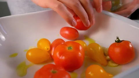 Woman hands adding tomatoes to baking sheet with oil to bake vegetables. Stock Footage 312456212