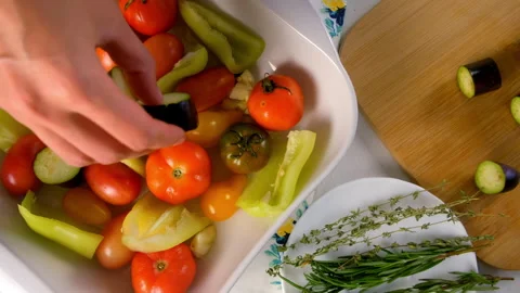 Woman hands adding vegetables to baking sheet with oil to bake vegetables. Stock Footage 312457236
