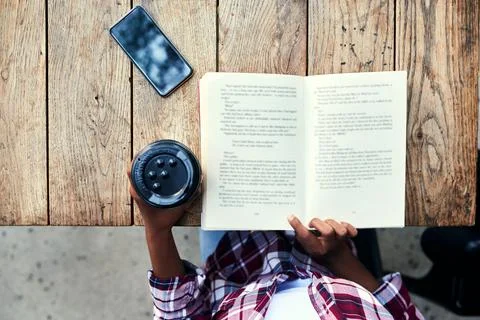Woman, hands and book of student reading with coffee for literature on wooden Stock Photos