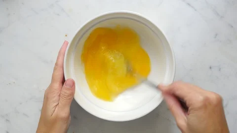Woman hands beating eggs with fork in a white bowl on white table. Egg culinary  Stock Footage 119301062