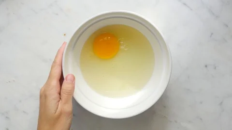 Woman hands beating eggs with fork in a white bowl on white table. Egg culinary  Video stock 119301129