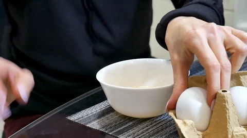 Woman hands cracking an egg into a white ceramic bowl at the kitchen Stock Footage 102803418