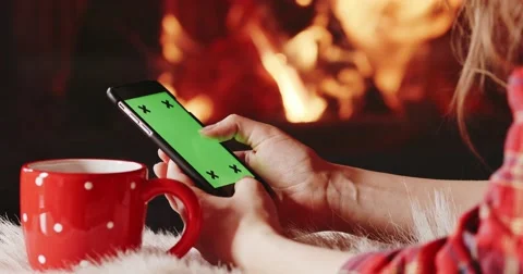 Woman Hands with Cup Using SmartPhone by the Burning Fireplace. 4K SLOW MOTION Stock Footage 69259577