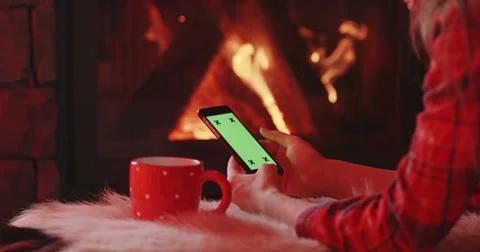 Woman Hands with Cup Using SmartPhone by the Burning Fireplace. 4K SLOW MOTION Vidéo 69260053