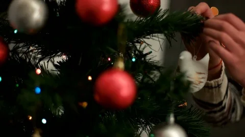 Woman hands decorating a Christmas tree red and silver toys in living room Stock Footage