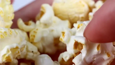 Woman hands holding and picking white salty popcorn close up Stock Footage 223546341
