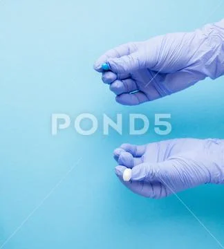 Woman hands in medical gloves giving two big pills. Blue and white. Make your Stock Photos