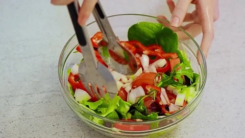Woman hands mixing fresh vegetable salad in a glass bowl Stock Footage