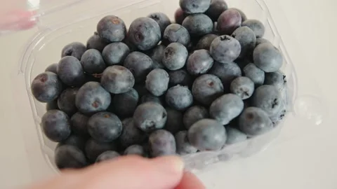 Woman hands open plastic container and takes blueberries 動画素材 161478383