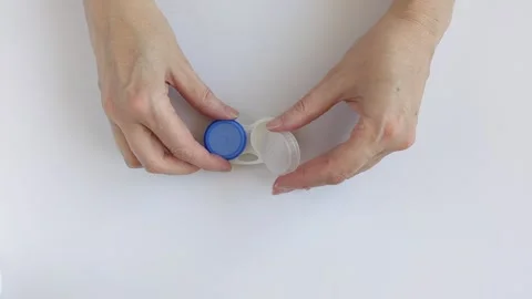Woman hands opens a container of contact lens solution Stock Footage 330748414