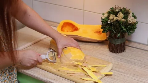 Female hands making butternut squash noodles with a vegetable peeler.Top  view Stock Photo - Alamy