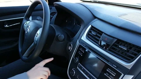 Woman hands pushing a start button in a car Nissan control panel adjust Stock Footage 73367804