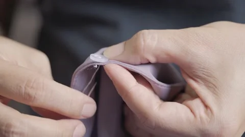 Woman hands putting needle with thread to the cloth button. Video stock 221994608