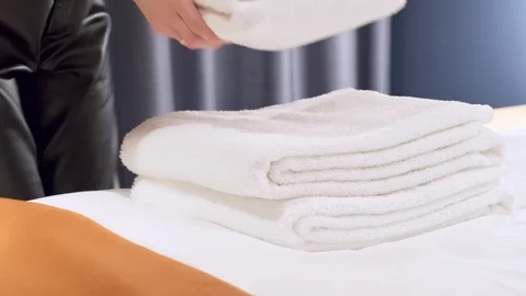 Woman hands putting stack of fresh clean white bath towels on the bed Stock Footage 125262439