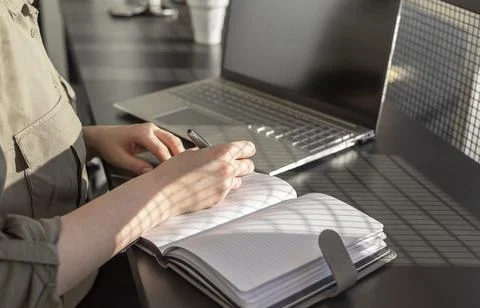 Woman hands taking notes in notebook and working on laptop. Online education and Stock Photos