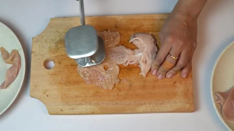 Woman Hands Tenderizing Raw Chicken Breast on Wooden Board with Metal Mallet Stock Footage 334323973