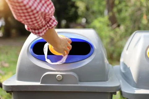 Woman hands throw empty plastic tumbler into the garbage Stock Photos